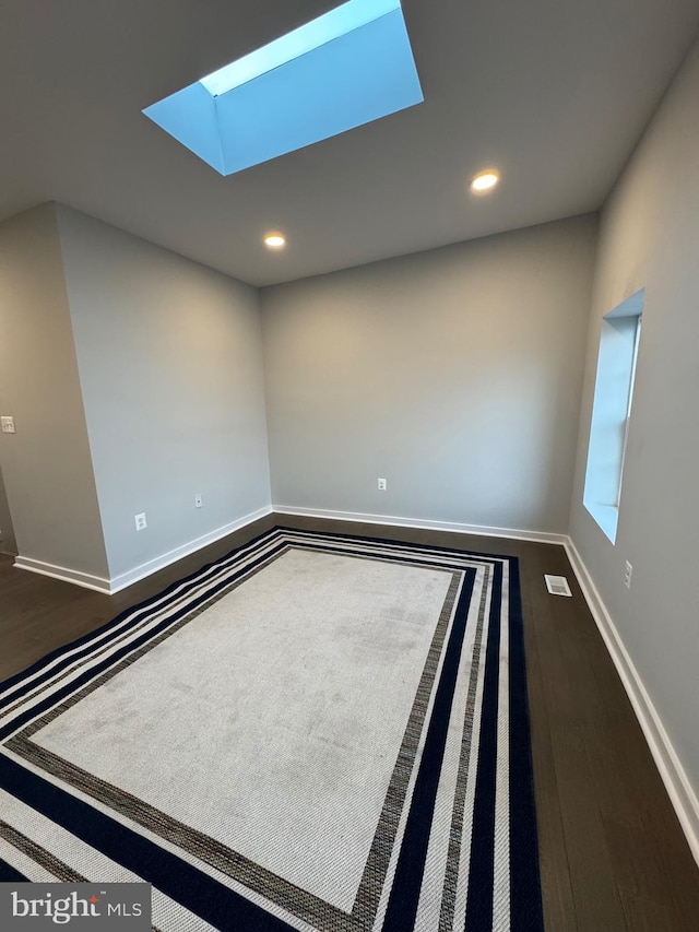 spare room with hardwood / wood-style floors and a skylight