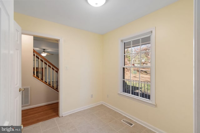 tiled empty room featuring ceiling fan