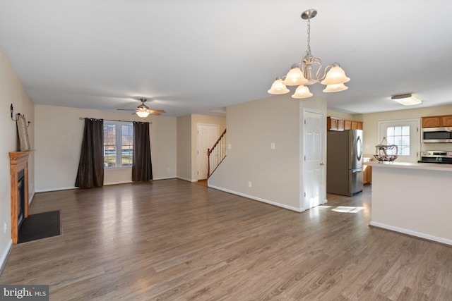 unfurnished living room with hardwood / wood-style floors and ceiling fan with notable chandelier