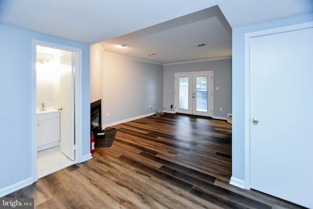 unfurnished living room featuring sink, dark hardwood / wood-style flooring, french doors, and ornamental molding