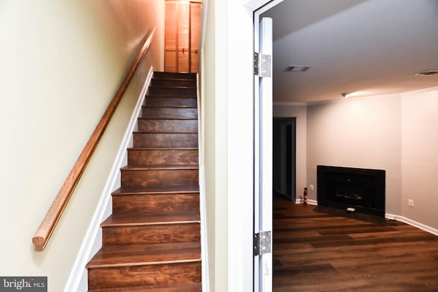 stairway with ornamental molding and hardwood / wood-style flooring