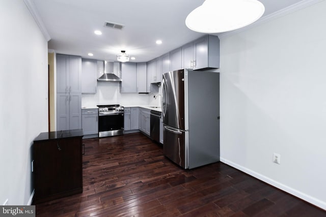 kitchen with dark wood-type flooring, crown molding, wall chimney exhaust hood, gray cabinets, and stainless steel appliances