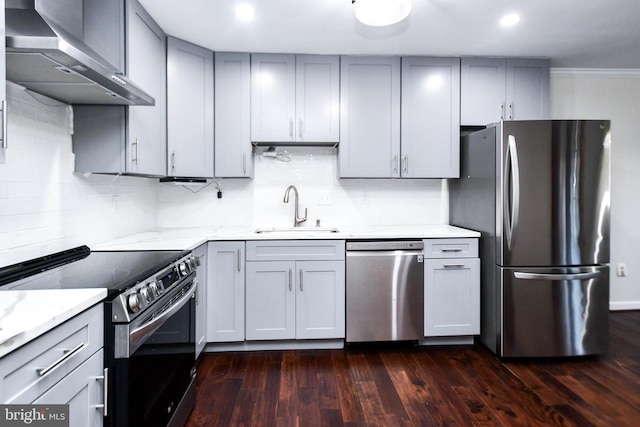 kitchen featuring gray cabinetry, dark wood-type flooring, wall chimney range hood, sink, and appliances with stainless steel finishes