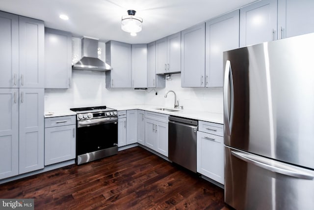 kitchen with gray cabinetry, sink, wall chimney exhaust hood, appliances with stainless steel finishes, and dark hardwood / wood-style flooring