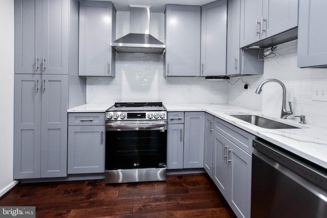 kitchen with gray cabinetry, wall chimney exhaust hood, dark hardwood / wood-style flooring, and appliances with stainless steel finishes