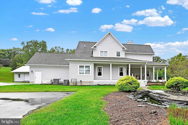 rear view of house featuring a porch, a yard, and central AC