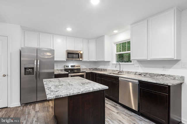 kitchen featuring appliances with stainless steel finishes, dark brown cabinets, sink, a center island, and light hardwood / wood-style floors