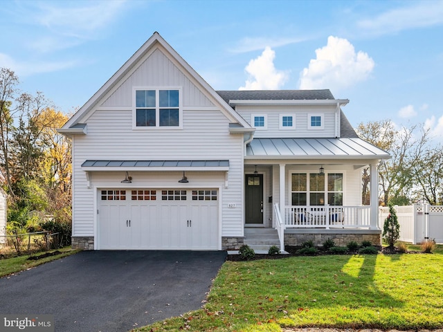 view of front of house featuring covered porch, a garage, and a front yard