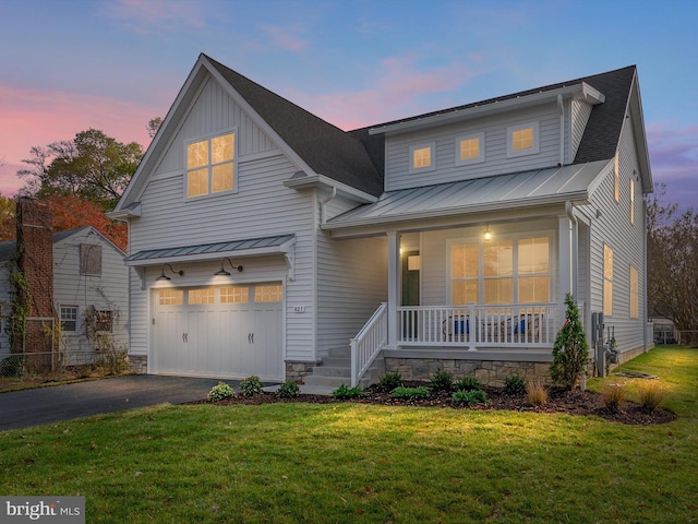 view of front of home featuring a lawn, covered porch, and a garage