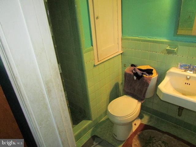 bathroom featuring walk in shower, toilet, and tile walls