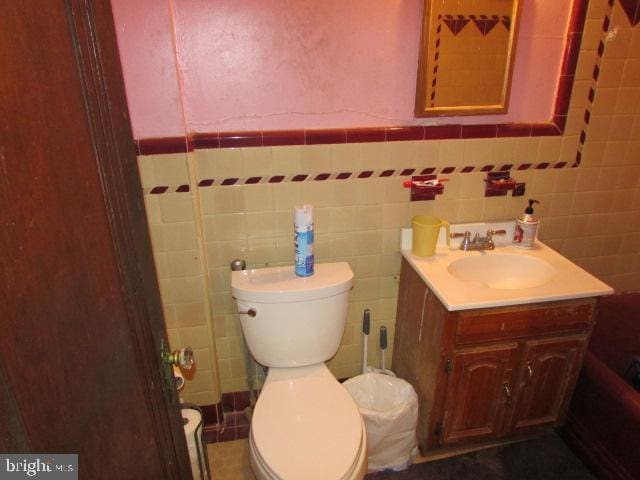 bathroom featuring vanity, toilet, and tile walls