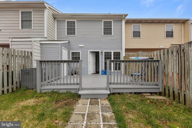 back of property with central air condition unit, a wooden deck, and a yard