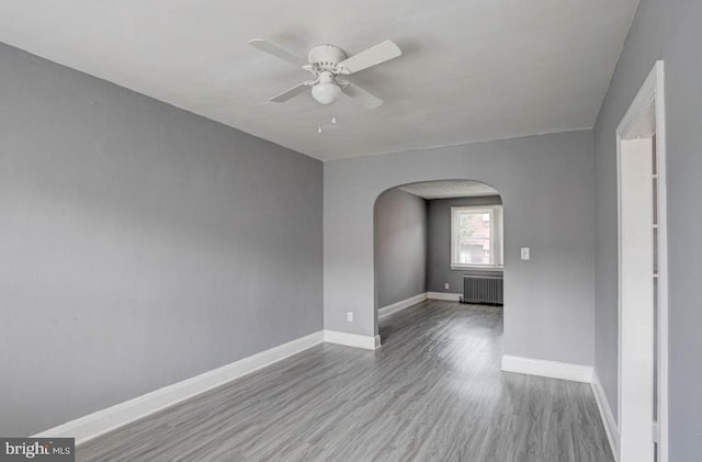 unfurnished room featuring radiator, ceiling fan, and light wood-type flooring