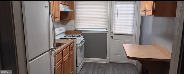 kitchen featuring dark wood-type flooring, a healthy amount of sunlight, and white appliances