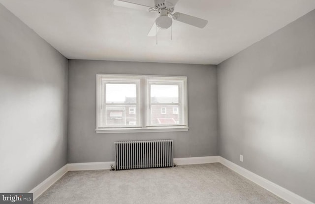 carpeted empty room featuring radiator and ceiling fan