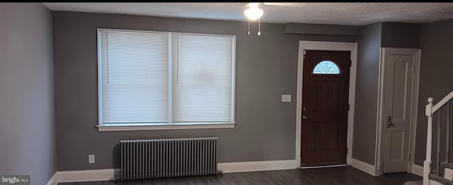 entryway with dark hardwood / wood-style floors, a textured ceiling, and radiator