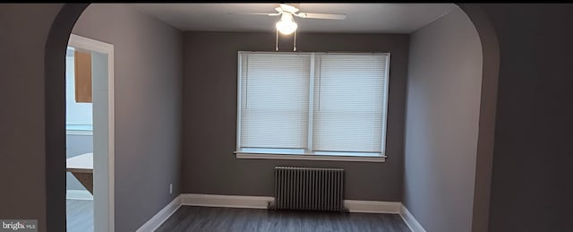 spare room with radiator heating unit, dark hardwood / wood-style flooring, and ceiling fan