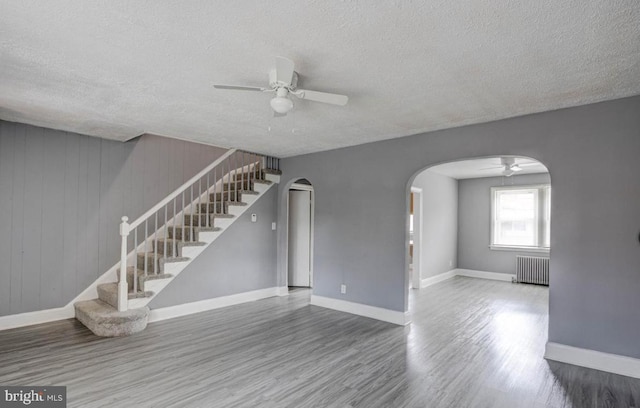 unfurnished living room with hardwood / wood-style floors, a textured ceiling, radiator, and ceiling fan