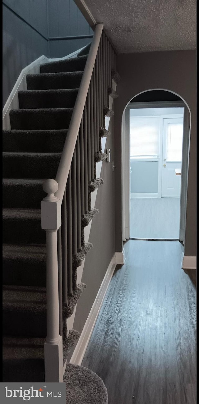 staircase featuring hardwood / wood-style flooring and a textured ceiling