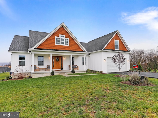 view of front of property with a garage, covered porch, and a front yard