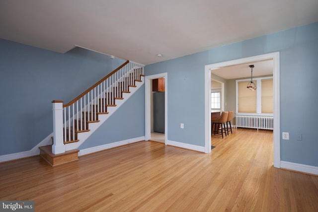 unfurnished living room featuring radiator and light hardwood / wood-style flooring