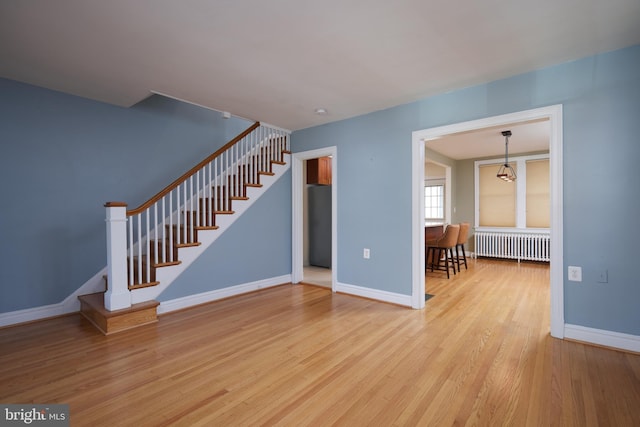 526 Powhatan Pl NW, Washington, DC 20011 - unfurnished living room featuring radiator heating unit, stairway, wood finished floors, and baseboards