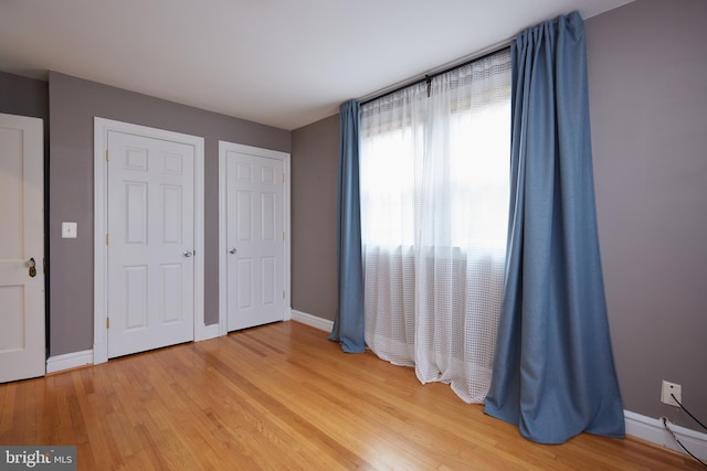 unfurnished bedroom featuring hardwood / wood-style flooring and multiple closets