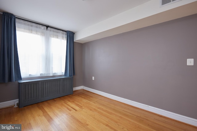 empty room with wood-type flooring and radiator