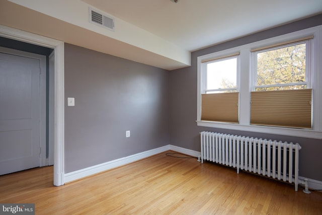 additional living space with radiator heating unit and light hardwood / wood-style floors