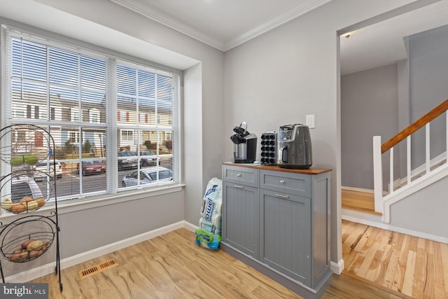 interior space featuring gray cabinets, light hardwood / wood-style flooring, and ornamental molding