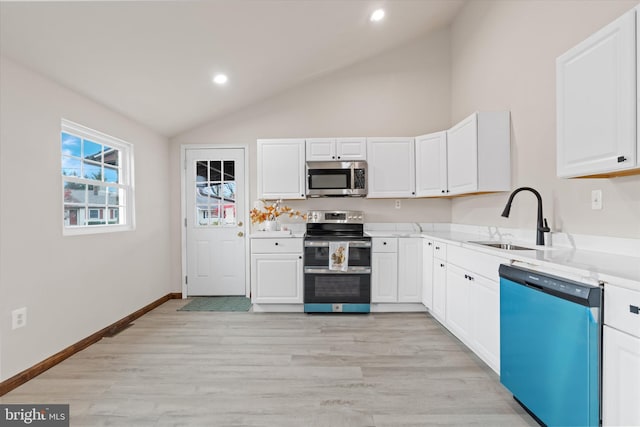 kitchen with white cabinetry, sink, lofted ceiling, and stainless steel appliances