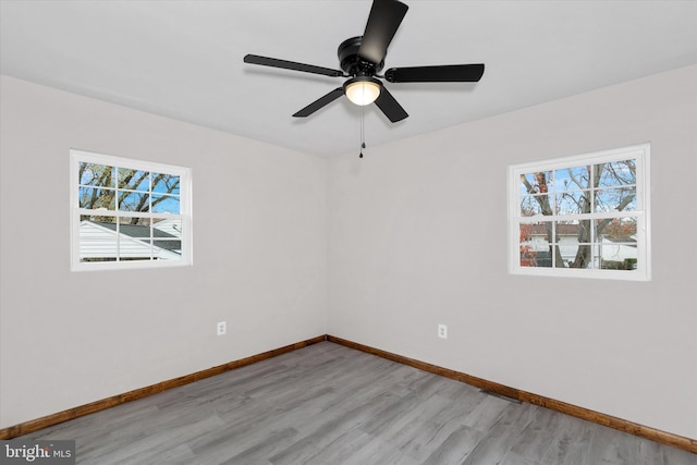 empty room with light wood-type flooring, ceiling fan, and a healthy amount of sunlight