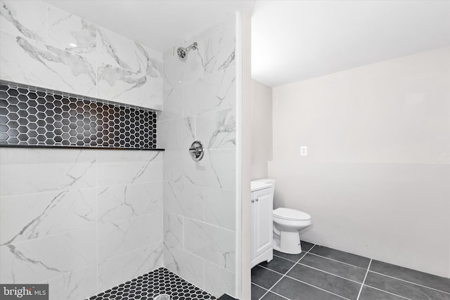 bathroom with tile patterned floors, vanity, toilet, and tiled shower