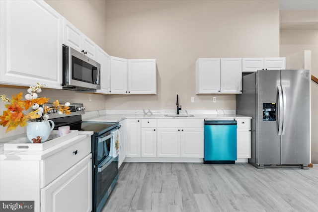 kitchen featuring appliances with stainless steel finishes, light hardwood / wood-style floors, white cabinetry, and sink