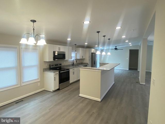 kitchen featuring a center island, sink, hanging light fixtures, white cabinetry, and stainless steel appliances