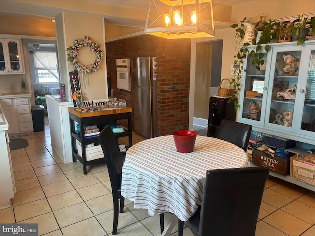 dining area with light tile patterned floors and brick wall