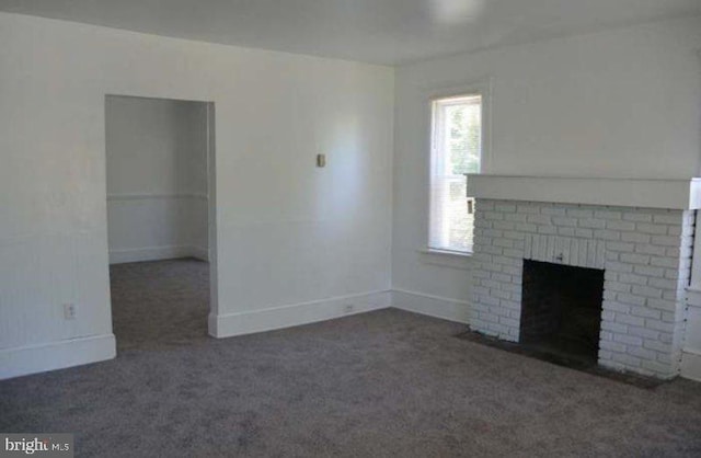 unfurnished living room with a fireplace and dark colored carpet