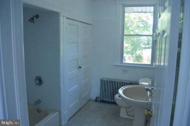 bathroom with radiator heating unit, toilet, and shower / washtub combination