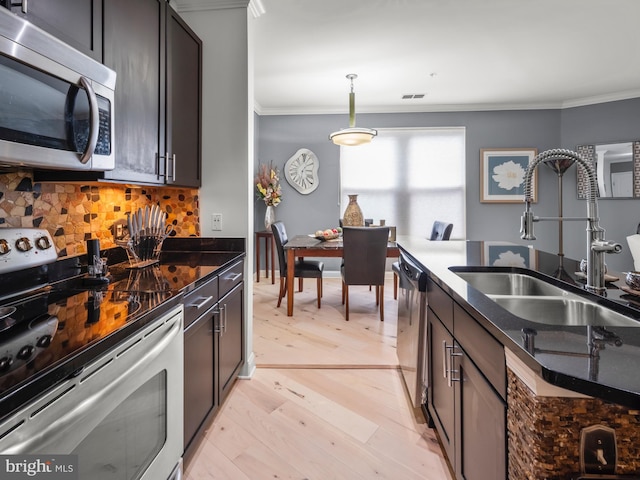 kitchen featuring dark brown cabinetry, sink, stainless steel appliances, pendant lighting, and light wood-type flooring