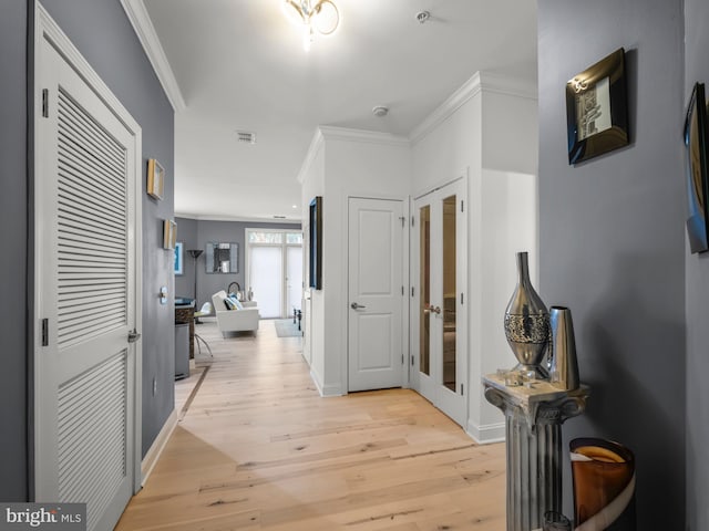 hall with light wood-type flooring, ornamental molding, and french doors