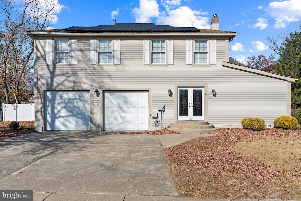 view of front property with french doors, a garage, and solar panels