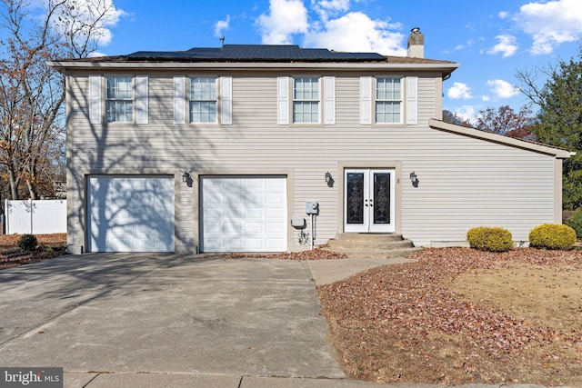 view of front property with french doors, a garage, and solar panels