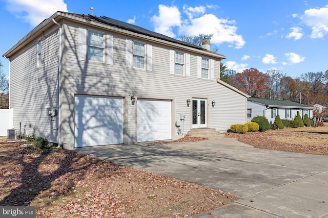 view of front of house with french doors, cooling unit, a garage, and solar panels