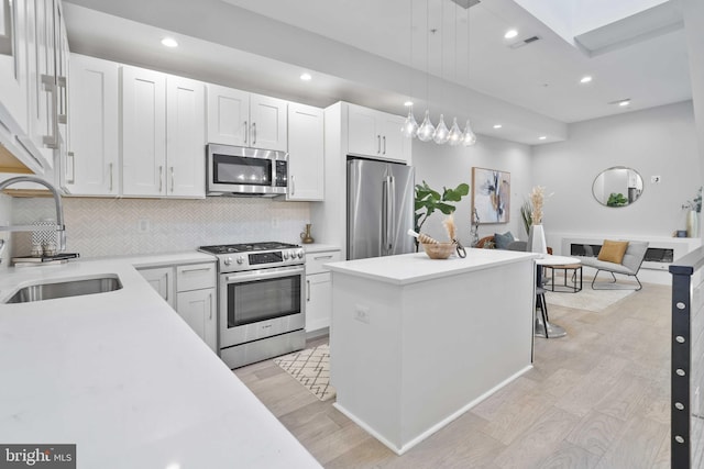 kitchen with white cabinetry, sink, decorative light fixtures, and stainless steel appliances