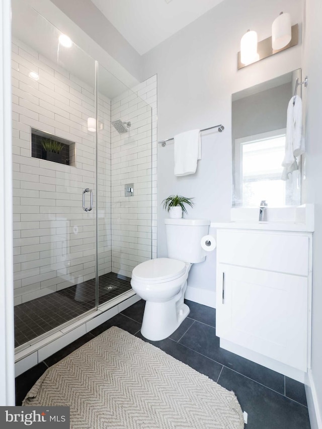 bathroom featuring tile patterned flooring, vanity, a shower with shower door, and toilet