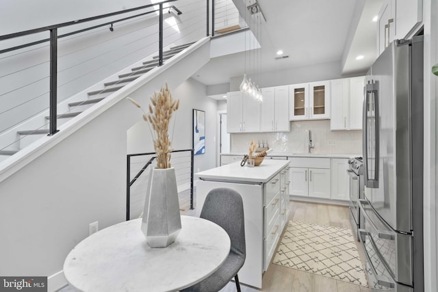 kitchen featuring sink, tasteful backsplash, a center island, stainless steel appliances, and white cabinets