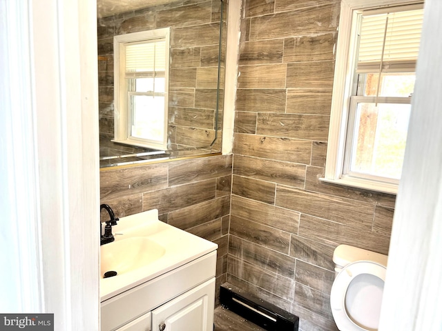 bathroom featuring a wealth of natural light, vanity, tile walls, and toilet