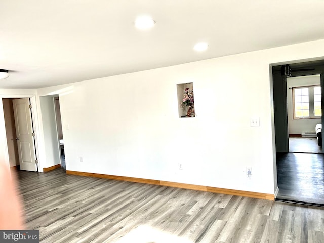 empty room featuring hardwood / wood-style flooring and baseboard heating