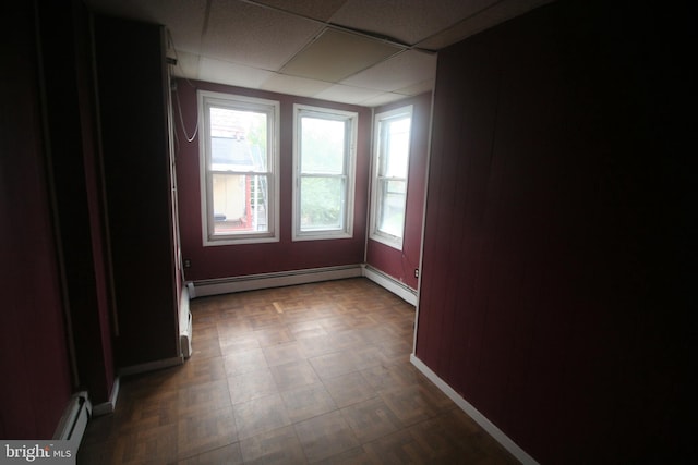 spare room with a drop ceiling and a baseboard heating unit