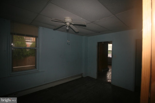 unfurnished room featuring a drop ceiling, ceiling fan, and baseboard heating